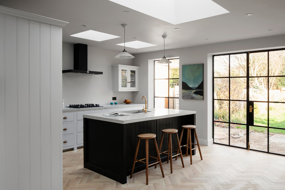 Design ideas for a medium sized modern single-wall open plan kitchen in London with shaker cabinets, concrete worktops, light hardwood flooring and an island.