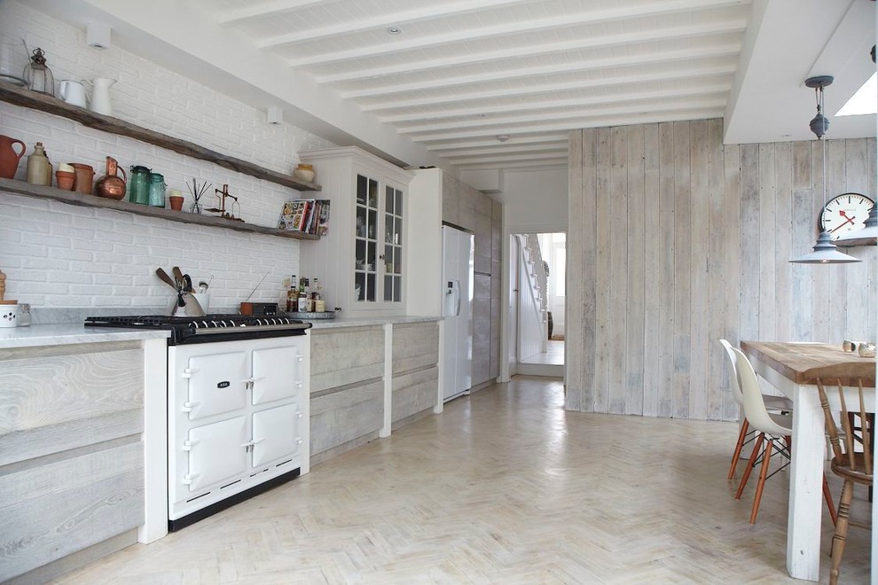 Diseño de cocina lineal nórdica con armarios con paneles lisos, puertas de armario de madera clara, salpicadero blanco, electrodomésticos blancos y suelo de madera pintada