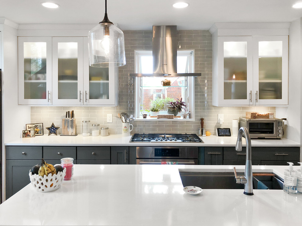This is an example of a large classic single-wall kitchen/diner in DC Metro with a submerged sink, shaker cabinets, grey cabinets, engineered stone countertops, grey splashback, metro tiled splashback, stainless steel appliances, light hardwood flooring, an island, brown floors and white worktops.