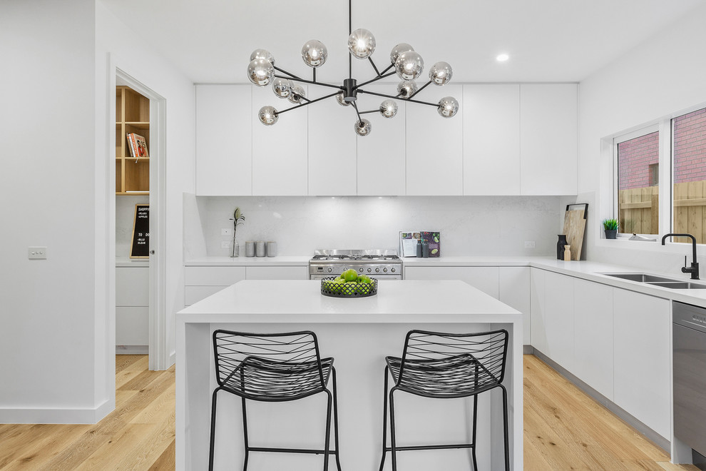 Photo of a small contemporary l-shaped kitchen/diner in Melbourne with white cabinets, engineered stone countertops, white splashback, marble splashback, stainless steel appliances, light hardwood flooring, an island, white worktops, a double-bowl sink, flat-panel cabinets and beige floors.