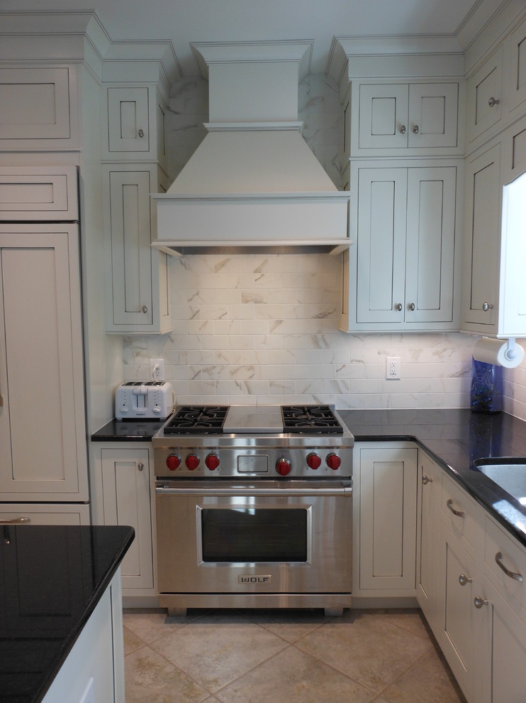 Example of a classic l-shaped eat-in kitchen design in Birmingham with an undermount sink, shaker cabinets, white cabinets, granite countertops, white backsplash, ceramic backsplash and stainless steel appliances
