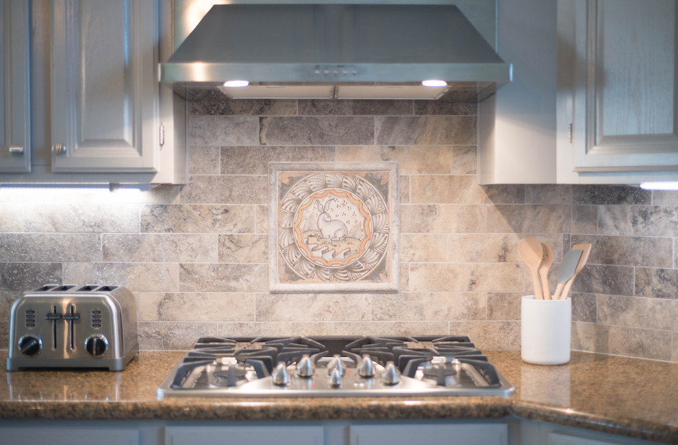 Exempel på ett avskilt, mellanstort klassiskt u-kök, med en undermonterad diskho, luckor med upphöjd panel, grå skåp, granitbänkskiva, beige stänkskydd, stänkskydd i travertin, rostfria vitvaror, klinkergolv i keramik och en köksö
