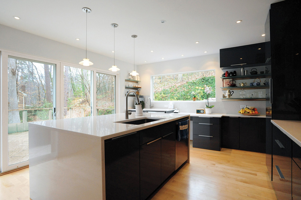 Example of a large trendy l-shaped light wood floor eat-in kitchen design in Atlanta with a drop-in sink, flat-panel cabinets, black cabinets, granite countertops, white backsplash, ceramic backsplash, black appliances and an island