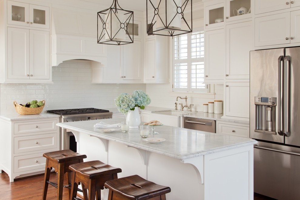 Kitchen - traditional l-shaped medium tone wood floor kitchen idea in Richmond with a farmhouse sink, shaker cabinets, white cabinets, marble countertops, white backsplash, subway tile backsplash, stainless steel appliances and an island