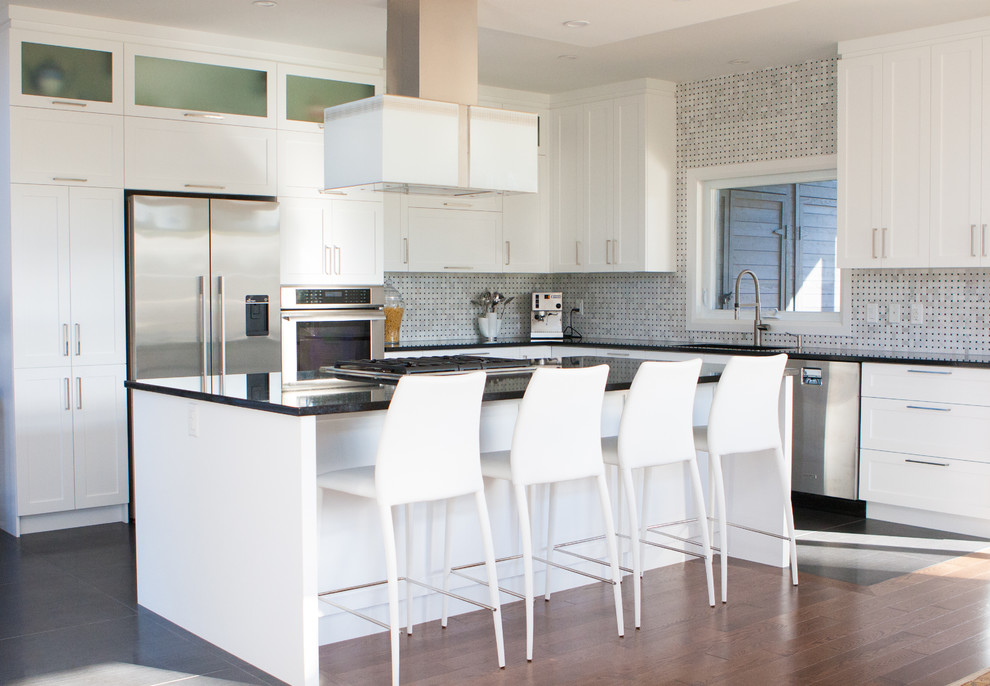 Example of a mid-sized transitional l-shaped kitchen design in Montreal with shaker cabinets, white cabinets, quartz countertops, white backsplash, stone tile backsplash, stainless steel appliances and an island
