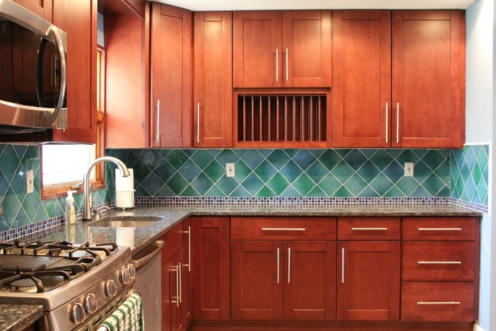 Exempel på ett avskilt, mellanstort klassiskt u-kök, med en undermonterad diskho, skåp i shakerstil, skåp i mellenmörkt trä, granitbänkskiva, grönt stänkskydd, stänkskydd i keramik, rostfria vitvaror och en halv köksö