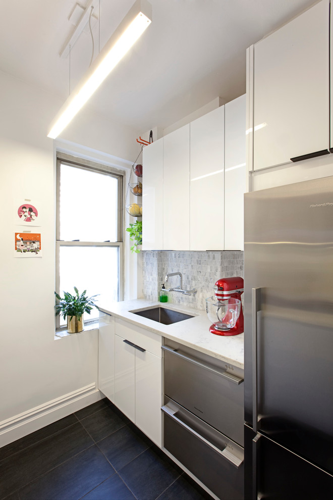Идея дизайна: отдельная, угловая кухня среднего размера в современном стиле с накладной мойкой, белыми фасадами, серым фартуком и белой техникой без острова