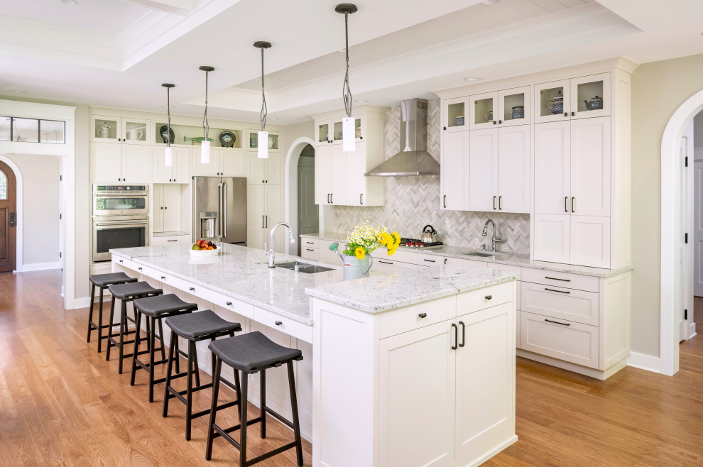 This is an example of a traditional l-shaped kitchen in Detroit with a submerged sink, shaker cabinets, white cabinets, grey splashback, stainless steel appliances, medium hardwood flooring, an island, brown floors, grey worktops and a drop ceiling.