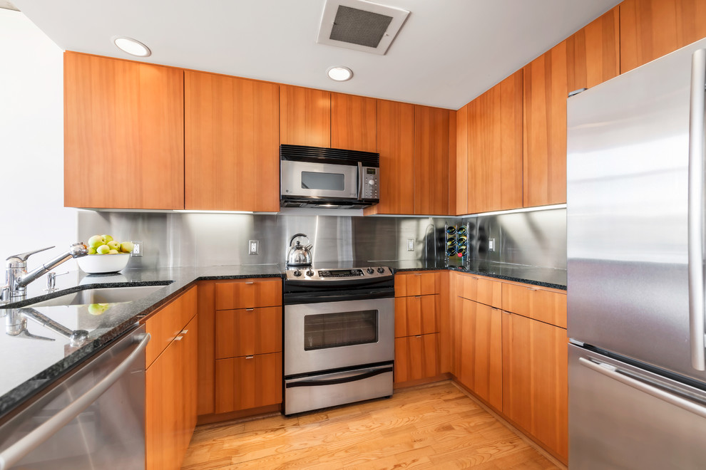 Design ideas for a contemporary u-shaped kitchen in San Francisco with a single-bowl sink, flat-panel cabinets, medium wood cabinets, metallic splashback, metal splashback and stainless steel appliances.