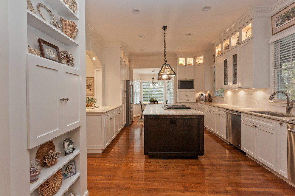 This is an example of an expansive classic u-shaped kitchen/diner in Charleston with an island, recessed-panel cabinets, white cabinets, recycled glass countertops, a submerged sink, white splashback, ceramic splashback, stainless steel appliances and medium hardwood flooring.