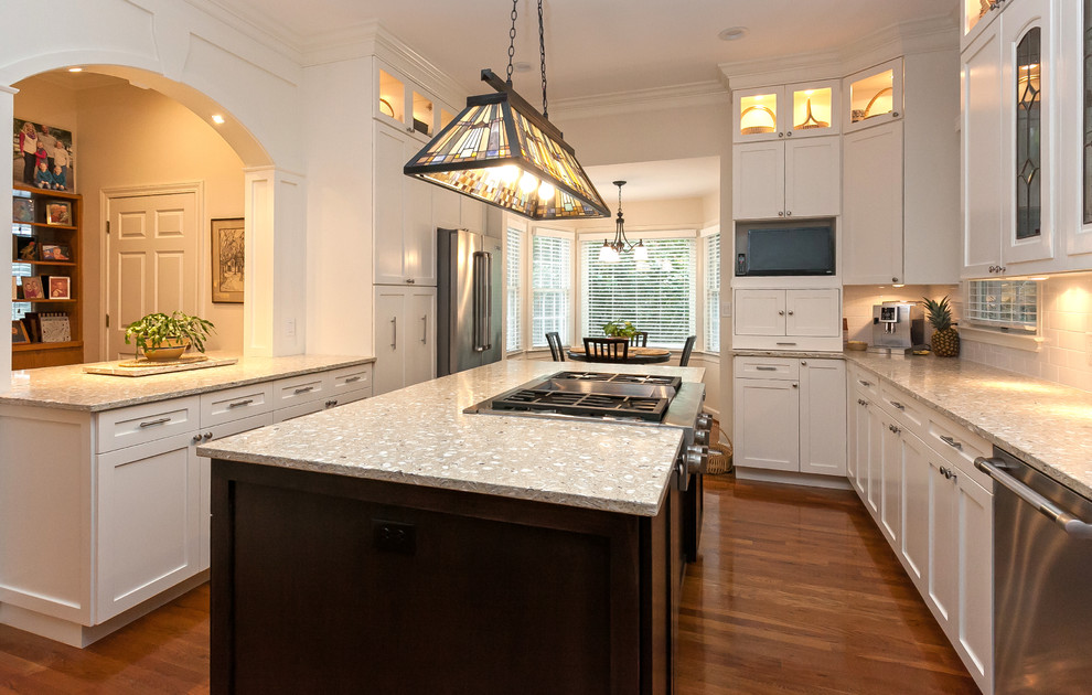 Expansive traditional u-shaped kitchen/diner in Charleston with an island, recessed-panel cabinets, white cabinets, recycled glass countertops, a submerged sink, white splashback, ceramic splashback, stainless steel appliances, medium hardwood flooring and beige floors.