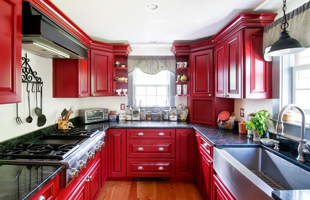 Inspiration for a large farmhouse u-shaped light wood floor and brown floor eat-in kitchen remodel in Boston with a farmhouse sink, raised-panel cabinets, red cabinets, wood countertops, white backsplash, stainless steel appliances and an island