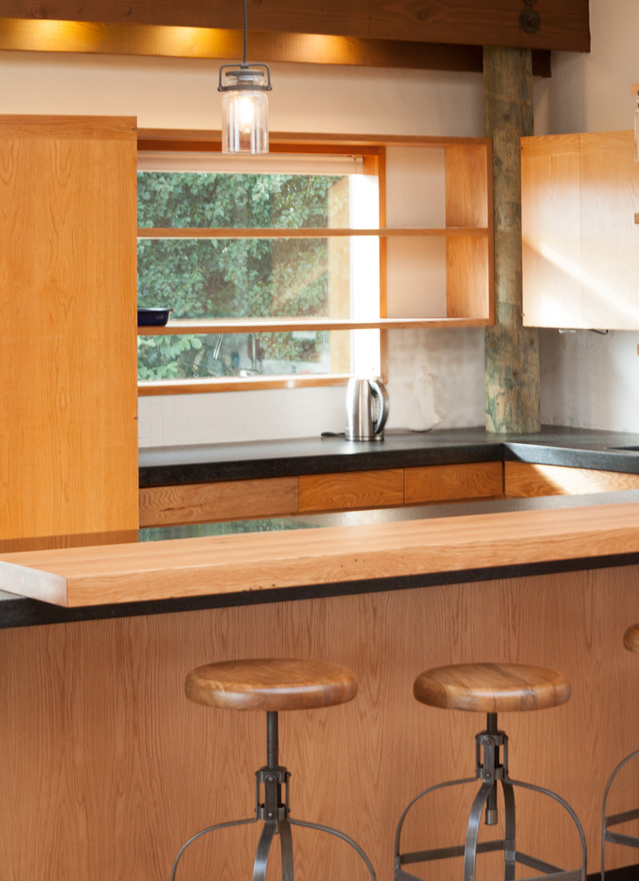 Eklektisk inredning av ett litet kök, med luckor med infälld panel, skåp i mellenmörkt trä, träbänkskiva, vitt stänkskydd, svarta vitvaror, mellanmörkt trägolv och en halv köksö
