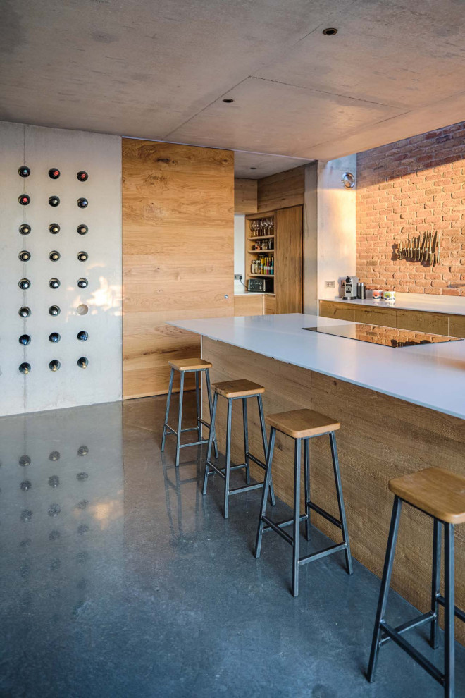 Large urban single-wall concrete floor open concept kitchen photo in Other with a drop-in sink, flat-panel cabinets, medium tone wood cabinets, white backsplash, black appliances, an island and white countertops