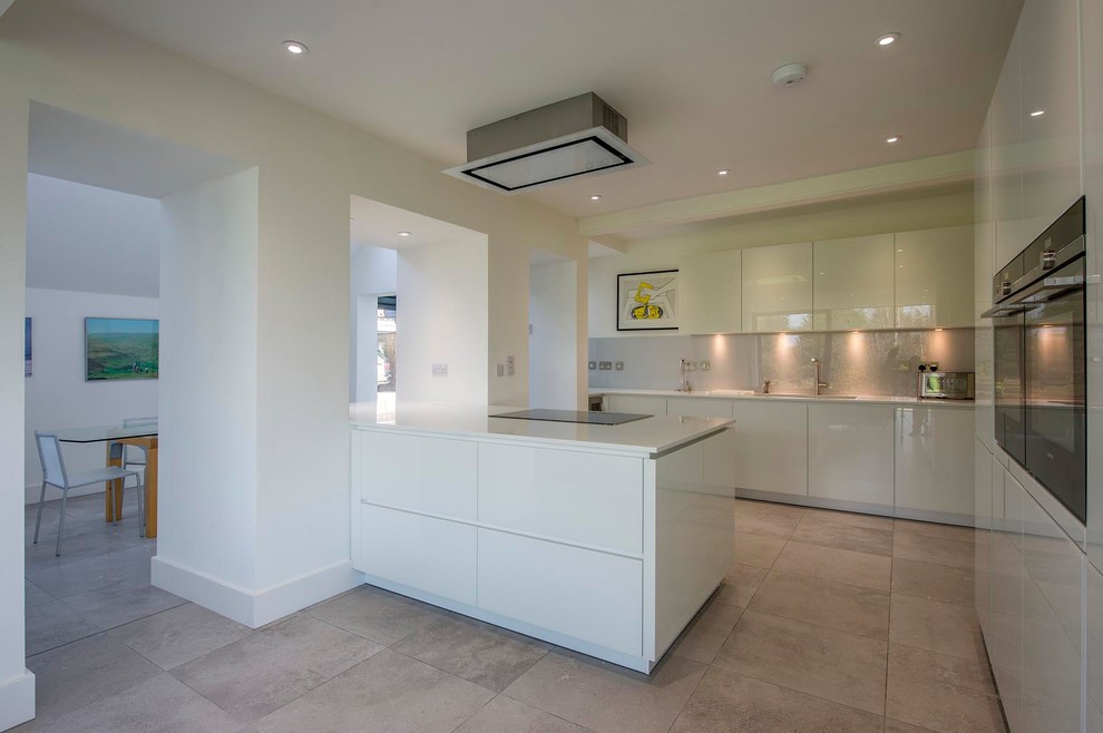 Inspiration for a contemporary l-shaped open plan kitchen in Other with flat-panel cabinets, white cabinets, black appliances, slate flooring, an island, a built-in sink and white splashback.