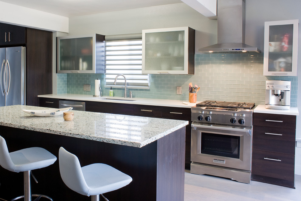 Esempio di una cucina minimal di medie dimensioni con lavello sottopiano, ante lisce, ante in legno bruno, top in vetro riciclato, paraspruzzi blu, paraspruzzi con piastrelle di vetro, elettrodomestici in acciaio inossidabile e parquet chiaro