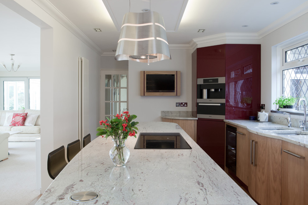Große Moderne Wohnküche mit Unterbauwaschbecken, flächenbündigen Schrankfronten, hellen Holzschränken, Granit-Arbeitsplatte, hellem Holzboden und Kücheninsel in Cornwall