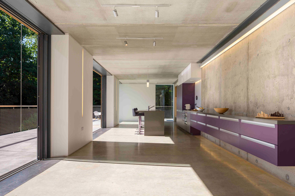 This is an example of a large contemporary single-wall kitchen in London with flat-panel cabinets, concrete flooring and an island.