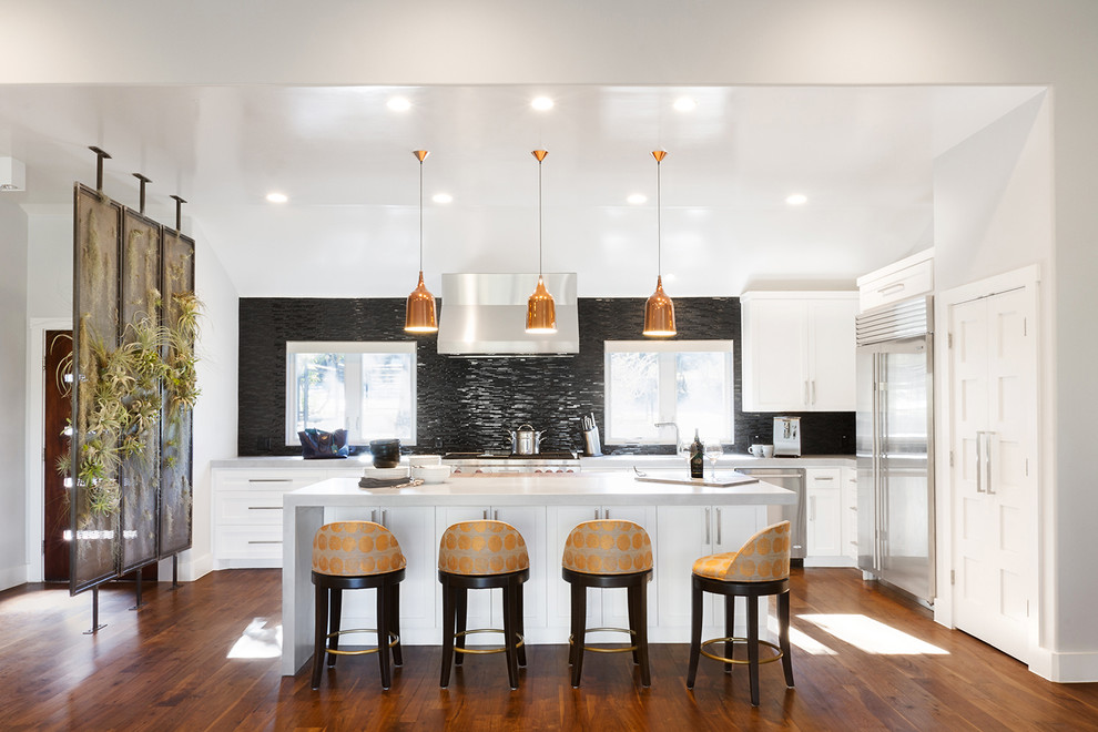 Foto di un cucina con isola centrale chic con ante in stile shaker, paraspruzzi nero, elettrodomestici in acciaio inossidabile e pavimento in legno massello medio