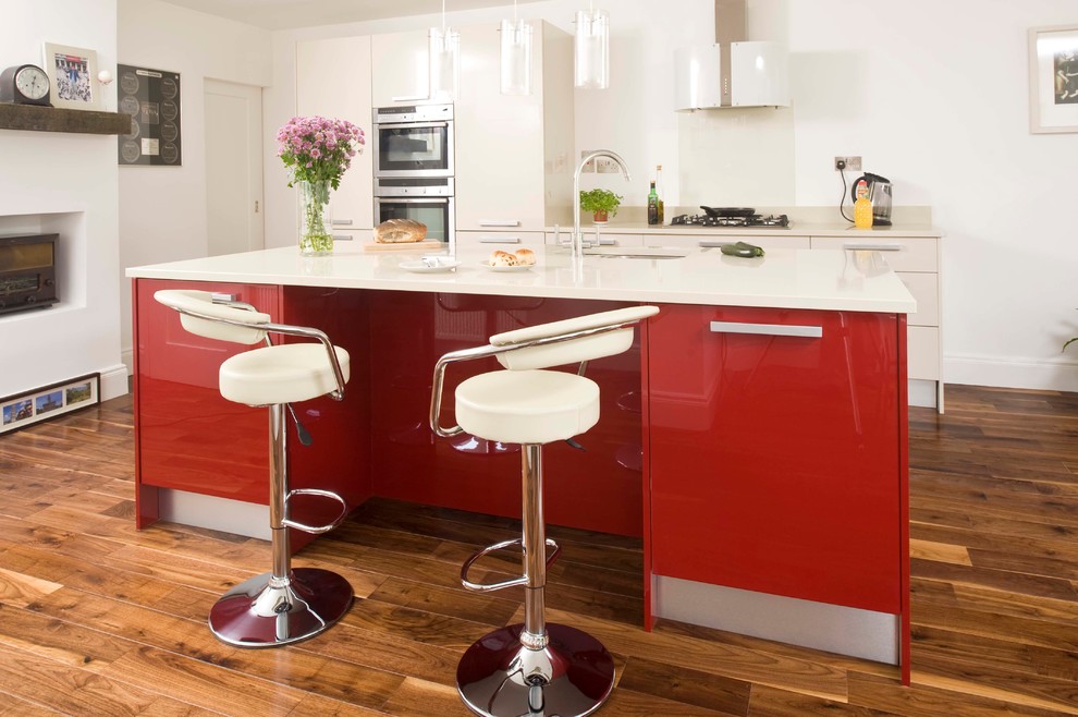 Immagine di una grande cucina design con lavello sottopiano, ante lisce, ante rosse, top in quarzo composito, paraspruzzi bianco, paraspruzzi con lastra di vetro e parquet scuro