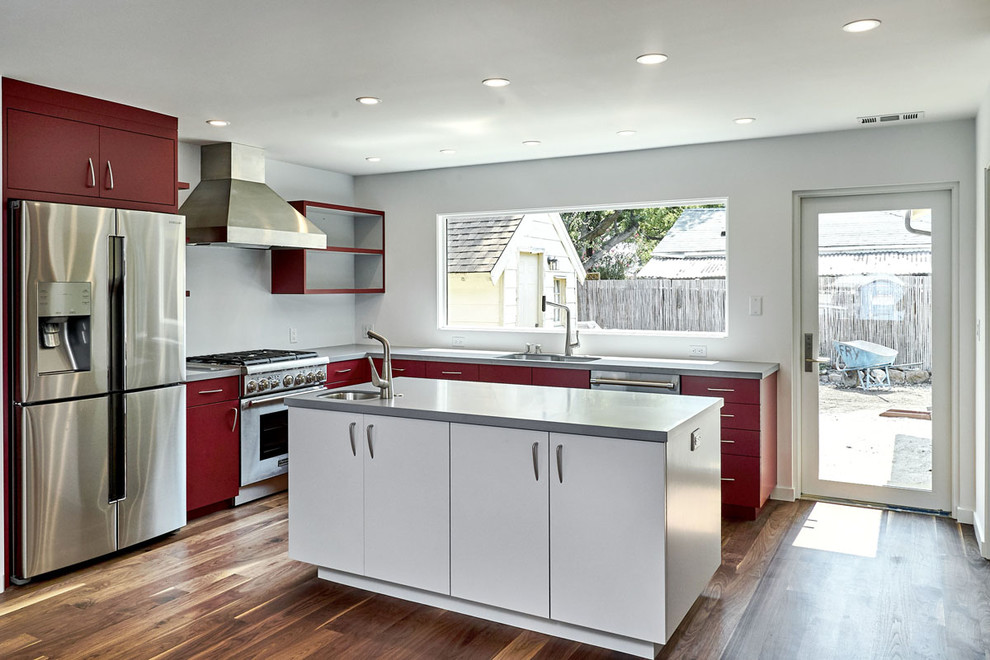 Inspiration for a mid-sized contemporary u-shaped medium tone wood floor and brown floor open concept kitchen remodel in San Francisco with an undermount sink, flat-panel cabinets, red cabinets, solid surface countertops, gray backsplash, stainless steel appliances, an island and gray countertops