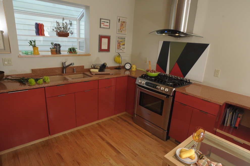 Idéer för mellanstora funkis kök, med en undermonterad diskho, släta luckor, orange skåp, granitbänkskiva, orange stänkskydd, stänkskydd i sten, rostfria vitvaror, ljust trägolv och en halv köksö