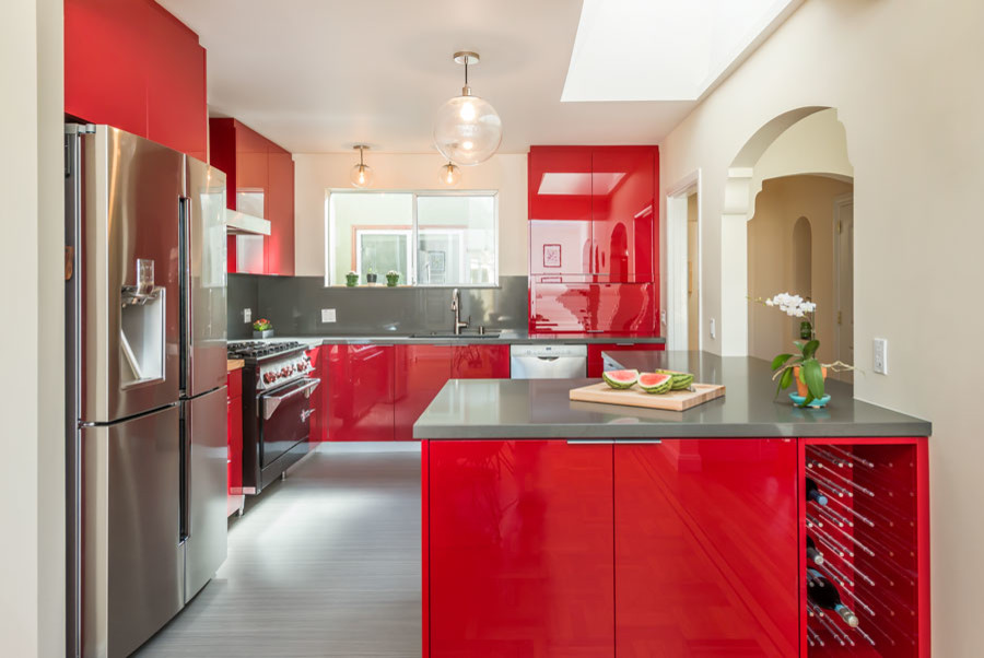 This is an example of a medium sized contemporary u-shaped kitchen/diner in San Francisco with a submerged sink, flat-panel cabinets, red cabinets, engineered stone countertops, grey splashback, stainless steel appliances, travertine splashback, lino flooring, a breakfast bar and grey floors.