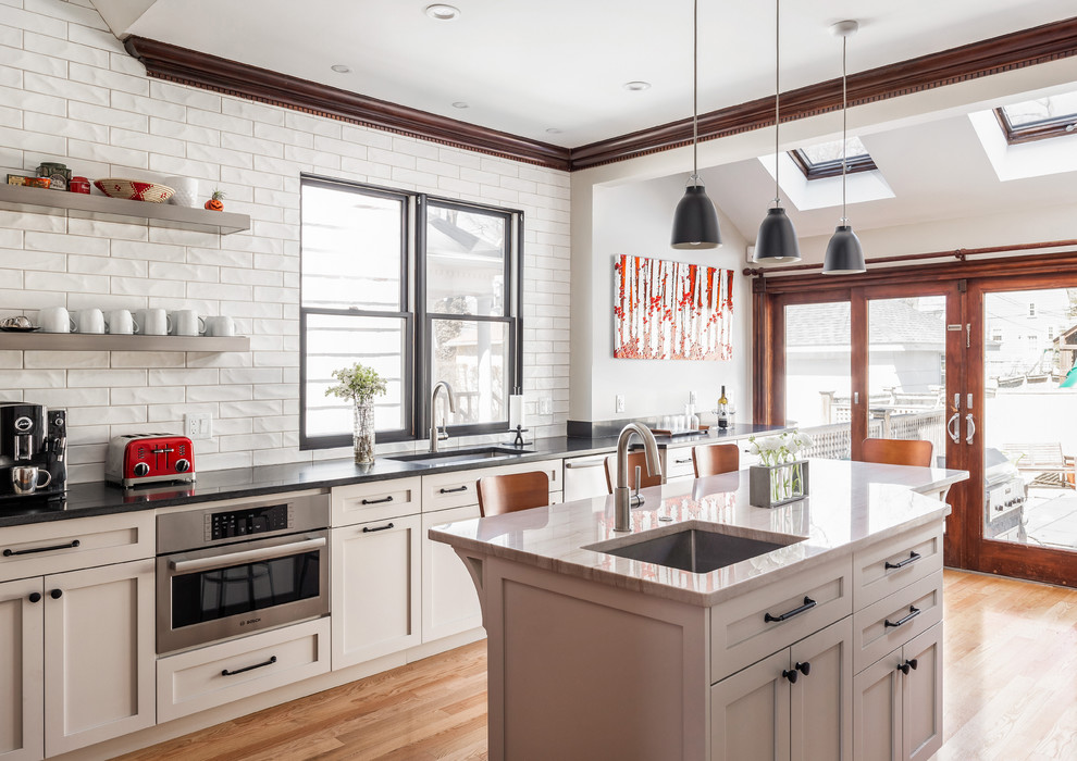 Inspiration for a large transitional medium tone wood floor and brown floor kitchen remodel in Boston with yellow cabinets, ceramic backsplash and an island