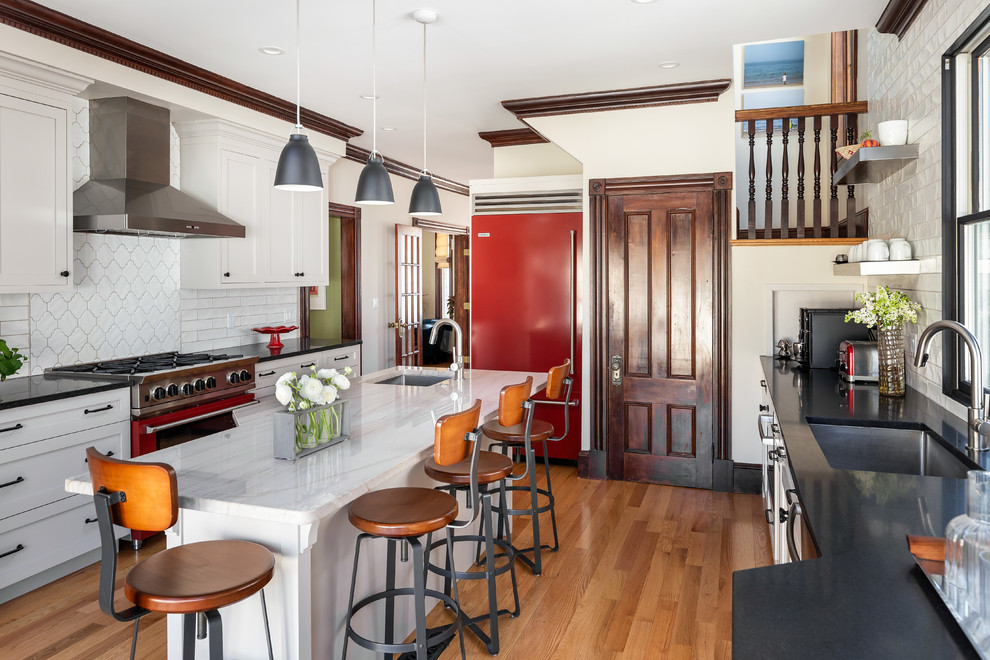 Große, Zweizeilige Klassische Küche mit Rückwand aus Keramikfliesen, braunem Holzboden, Kücheninsel, braunem Boden, Unterbauwaschbecken, Schrankfronten im Shaker-Stil, weißen Schränken, Küchenrückwand in Weiß und schwarzer Arbeitsplatte in Boston