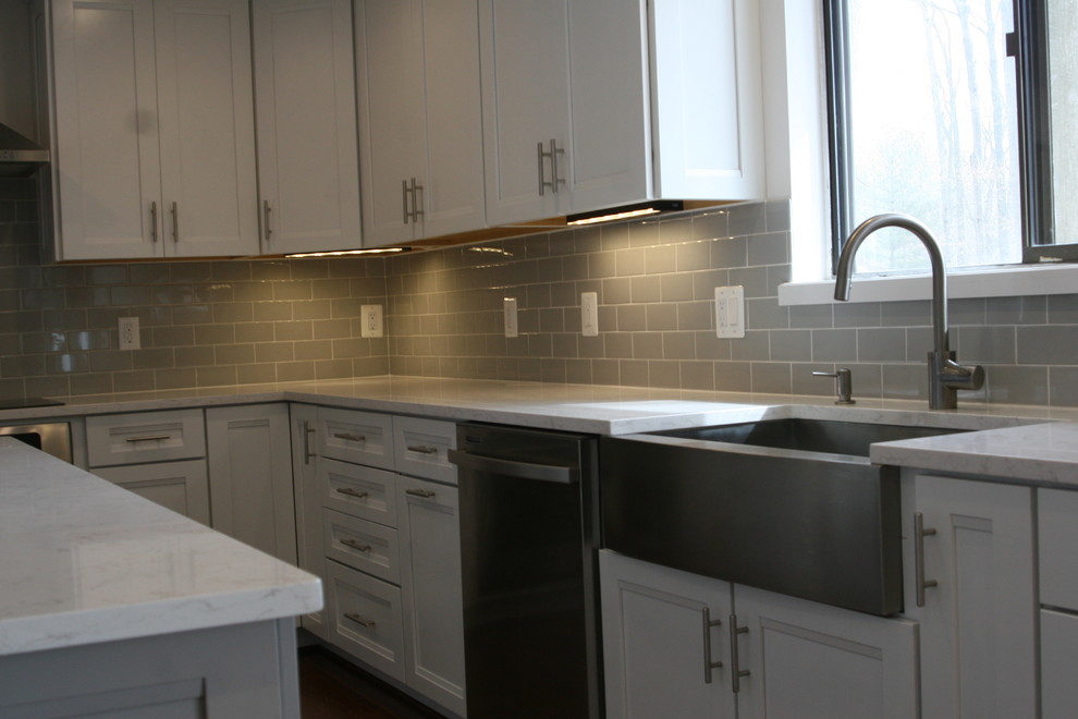 Example of a mid-sized minimalist u-shaped eat-in kitchen design in Baltimore with a farmhouse sink, recessed-panel cabinets, white cabinets, quartz countertops, beige backsplash, subway tile backsplash, stainless steel appliances and an island