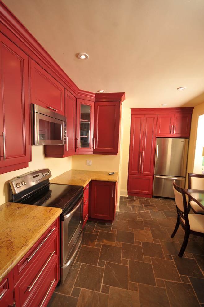 Inredning av ett modernt stort kök, med en undermonterad diskho, släta luckor, röda skåp, granitbänkskiva, beige stänkskydd, rostfria vitvaror och klinkergolv i porslin