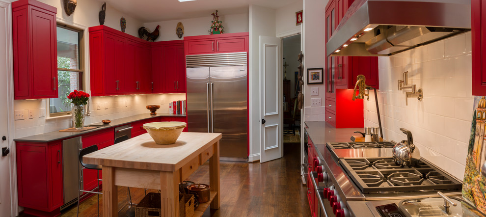Idées déco pour une cuisine américaine classique en U avec un placard avec porte à panneau encastré, des portes de placard rouges, un plan de travail en quartz et un électroménager en acier inoxydable.