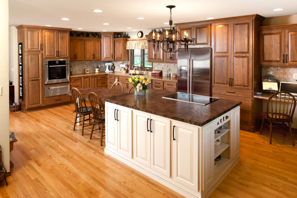 Foto på ett stort amerikanskt kök, med en undermonterad diskho, luckor med upphöjd panel, skåp i mörkt trä, beige stänkskydd, stänkskydd i keramik, rostfria vitvaror, ljust trägolv, en köksö och beiget golv
