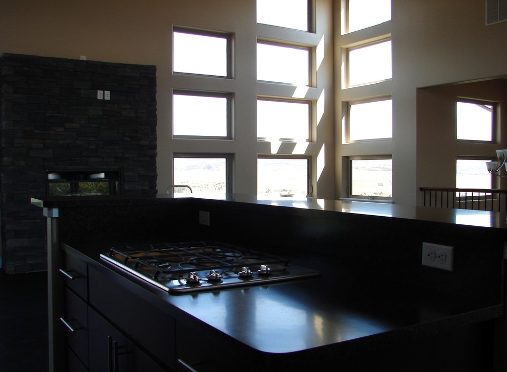 Example of a trendy l-shaped eat-in kitchen design in Denver with flat-panel cabinets, dark wood cabinets, laminate countertops and stainless steel appliances