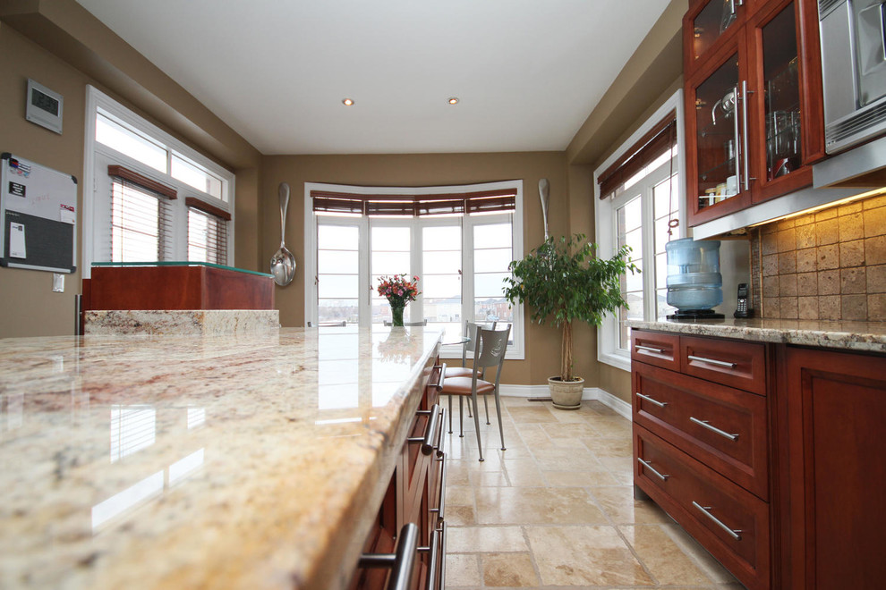 Example of a large transitional galley travertine floor and multicolored floor eat-in kitchen design in Toronto with a double-bowl sink, glass-front cabinets, red cabinets, granite countertops, beige backsplash, travertine backsplash, stainless steel appliances, two islands and beige countertops