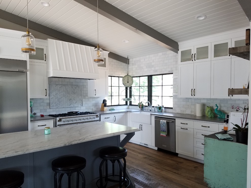 Foto på ett stort lantligt l-kök, med en rustik diskho, skåp i shakerstil, vita skåp, marmorbänkskiva, grått stänkskydd, stänkskydd i tunnelbanekakel, rostfria vitvaror, mellanmörkt trägolv, en köksö och brunt golv