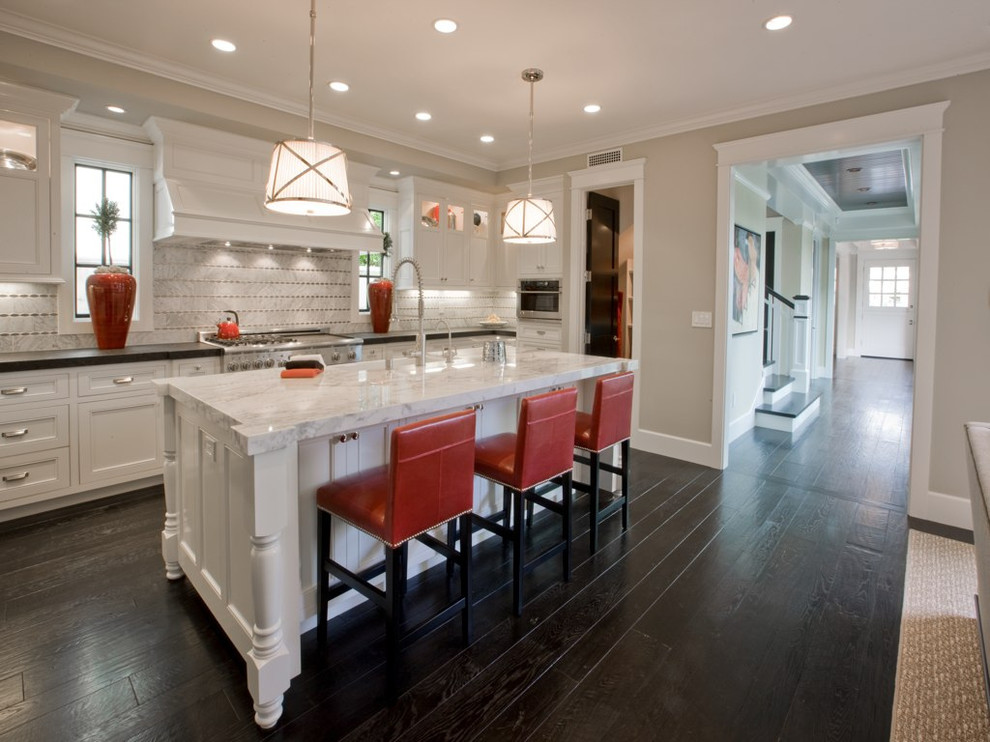Example of a mid-sized classic dark wood floor eat-in kitchen design in Orange County with a farmhouse sink, shaker cabinets, white cabinets, marble countertops, gray backsplash and an island