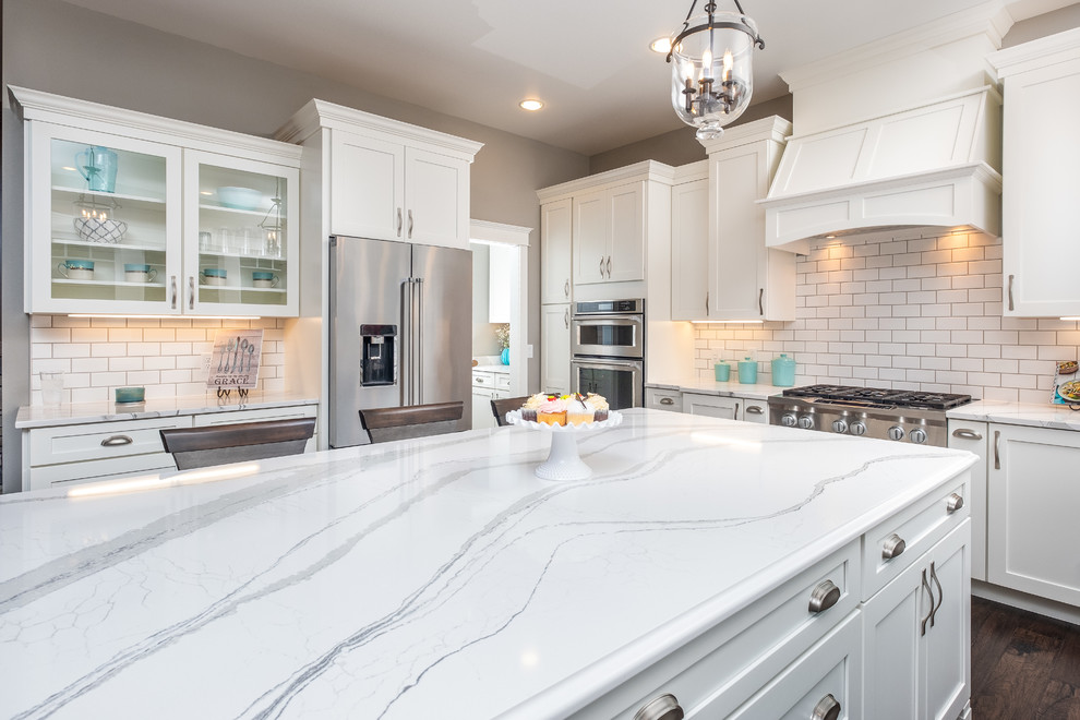 Inspiration for a large timeless u-shaped open concept kitchen remodel in Other with a farmhouse sink, shaker cabinets, white cabinets, quartzite countertops, white backsplash, subway tile backsplash, stainless steel appliances, an island and white countertops