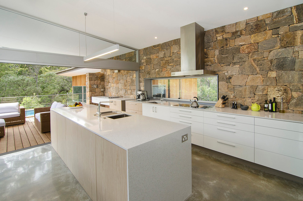 Foto på ett funkis kök, med en köksö, en undermonterad diskho, släta luckor, vita skåp och betonggolv