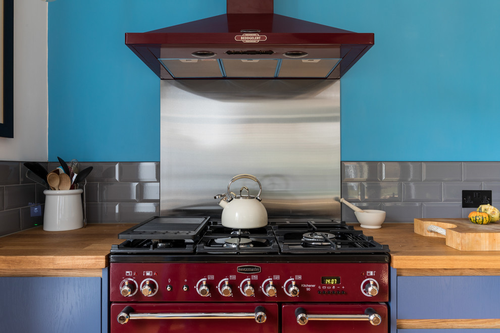 Modern inredning av ett litet kök, med en integrerad diskho, släta luckor, skåp i mellenmörkt trä, bänkskiva i kvartsit, grått stänkskydd, färgglada vitvaror, mellanmörkt trägolv och flerfärgat golv