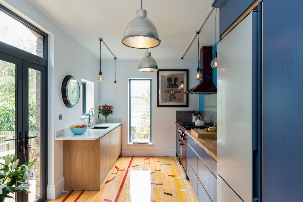 Zweizeilige, Kleine Moderne Wohnküche mit integriertem Waschbecken, flächenbündigen Schrankfronten, hellbraunen Holzschränken, Quarzit-Arbeitsplatte, Küchenrückwand in Grau, bunten Elektrogeräten, braunem Holzboden und buntem Boden in Surrey