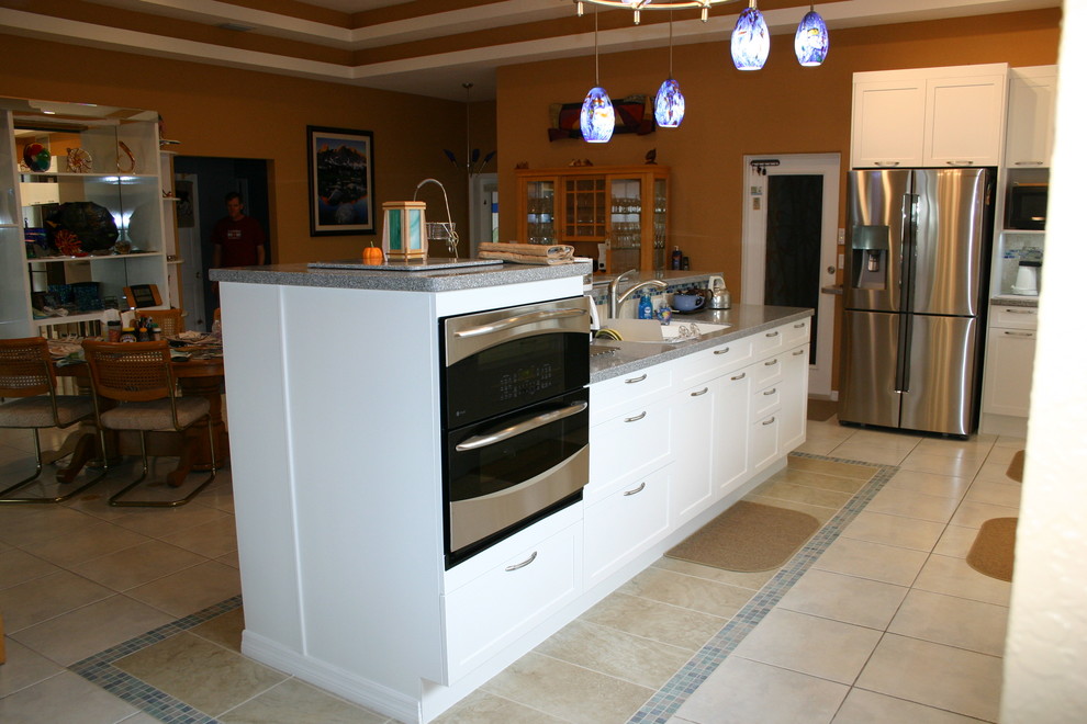 This is an example of a medium sized traditional l-shaped open plan kitchen in Tampa with an integrated sink, shaker cabinets, white cabinets, ceramic splashback, stainless steel appliances, porcelain flooring and an island.