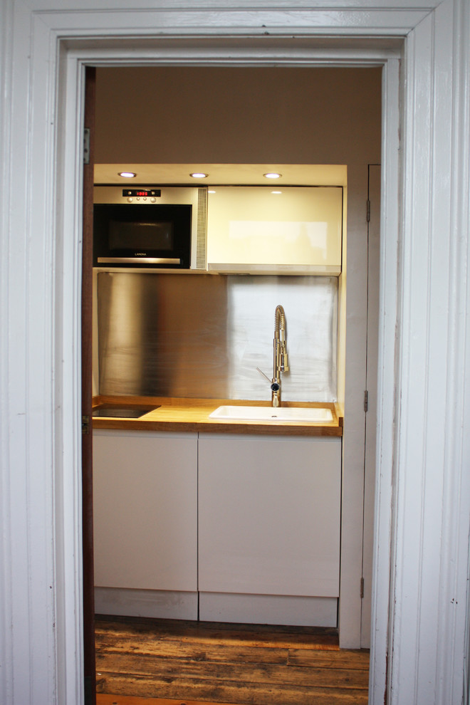 Immagine di una piccola cucina nordica chiusa con ante lisce, top in legno, pavimento in laminato, nessuna isola, pavimento marrone e top marrone