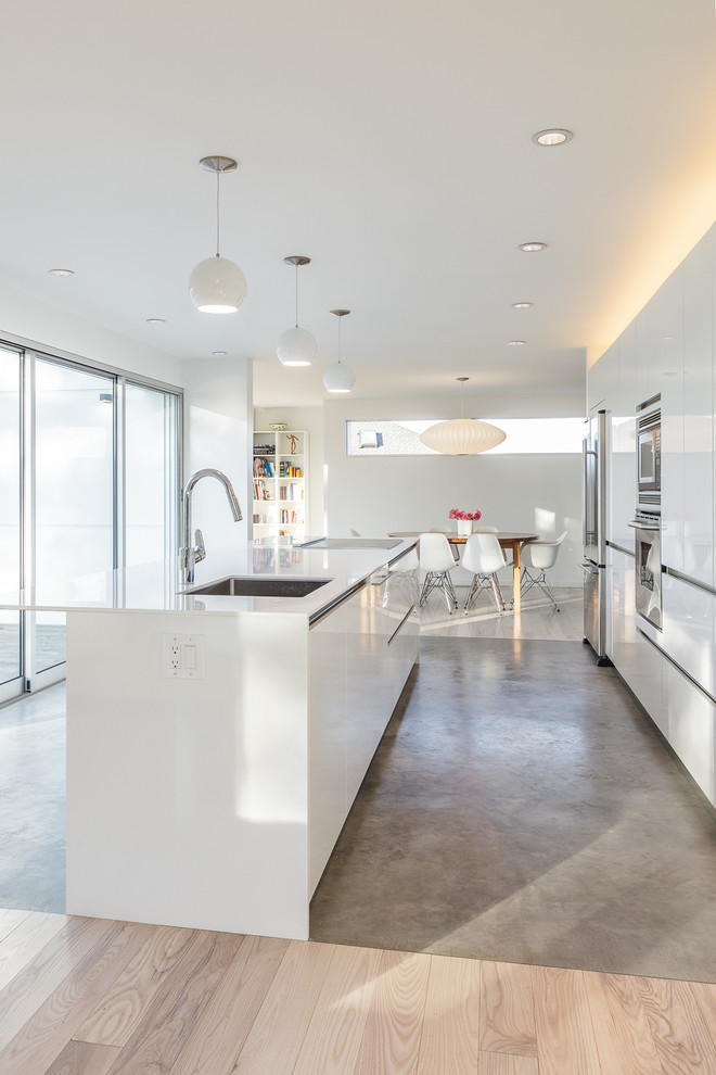Zweizeilige Moderne Wohnküche mit Unterbauwaschbecken, flächenbündigen Schrankfronten, weißen Schränken, Küchengeräten aus Edelstahl und Kücheninsel in Seattle