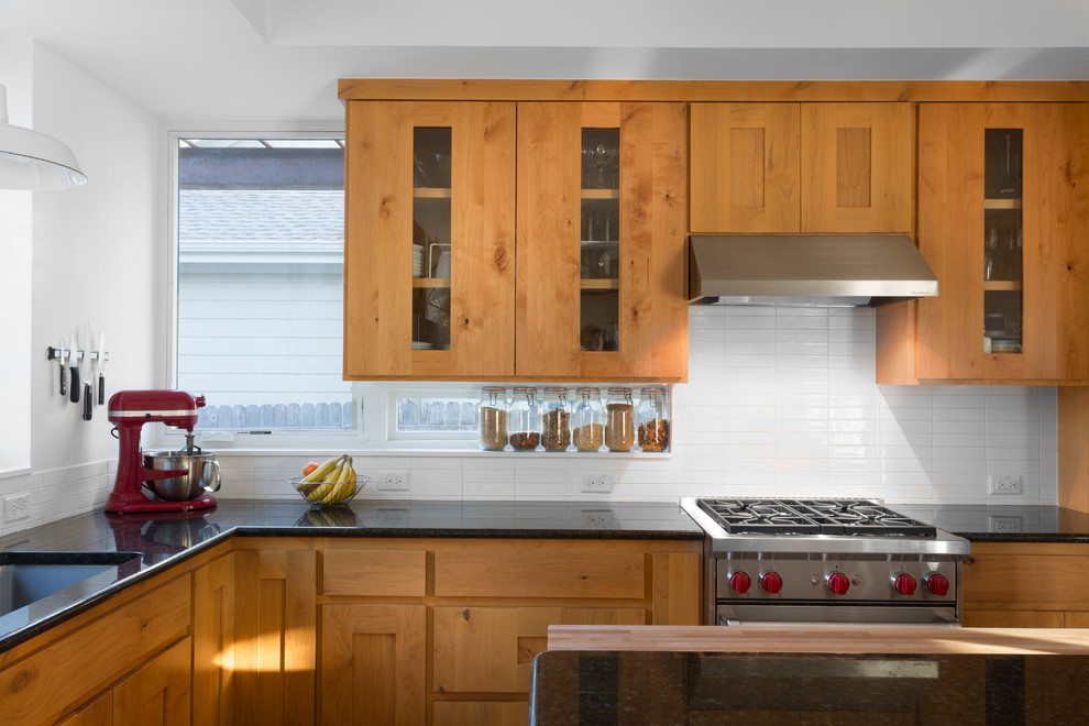 オースティンにあるコンテンポラリースタイルのおしゃれなL型キッチン (落し込みパネル扉のキャビネット、中間色木目調キャビネット、白いキッチンパネル) の写真