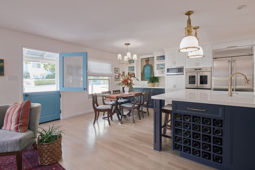 Photo of a medium sized traditional l-shaped open plan kitchen in San Francisco with a submerged sink, recessed-panel cabinets, blue cabinets, engineered stone countertops, blue splashback, ceramic splashback, stainless steel appliances, light hardwood flooring, an island, beige floors and white worktops.