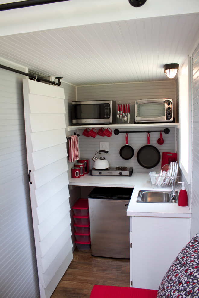 他の地域にあるエクレクティックスタイルのおしゃれなL型キッチン (ドロップインシンク、白いキャビネット、シルバーの調理設備) の写真