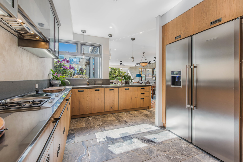 Photo of a world-inspired u-shaped enclosed kitchen in Perth with flat-panel cabinets, medium wood cabinets, stainless steel appliances, no island, beige floors and grey worktops.
