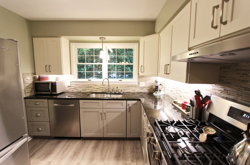 Example of a small transitional u-shaped laminate floor and gray floor enclosed kitchen design in Cleveland with flat-panel cabinets, no island, a drop-in sink, gray cabinets, laminate countertops, multicolored backsplash, glass tile backsplash, stainless steel appliances and black countertops