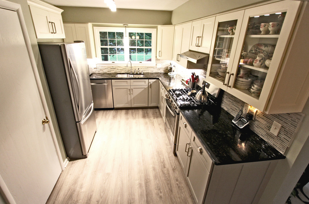 クリーブランドにあるお手頃価格の小さなトランジショナルスタイルのおしゃれなキッチン (フラットパネル扉のキャビネット、緑のキャビネット、ラミネートの床、アイランドなし、グレーの床、ドロップインシンク、ラミネートカウンター、マルチカラーのキッチンパネル、ガラスタイルのキッチンパネル、シルバーの調理設備、黒いキッチンカウンター) の写真